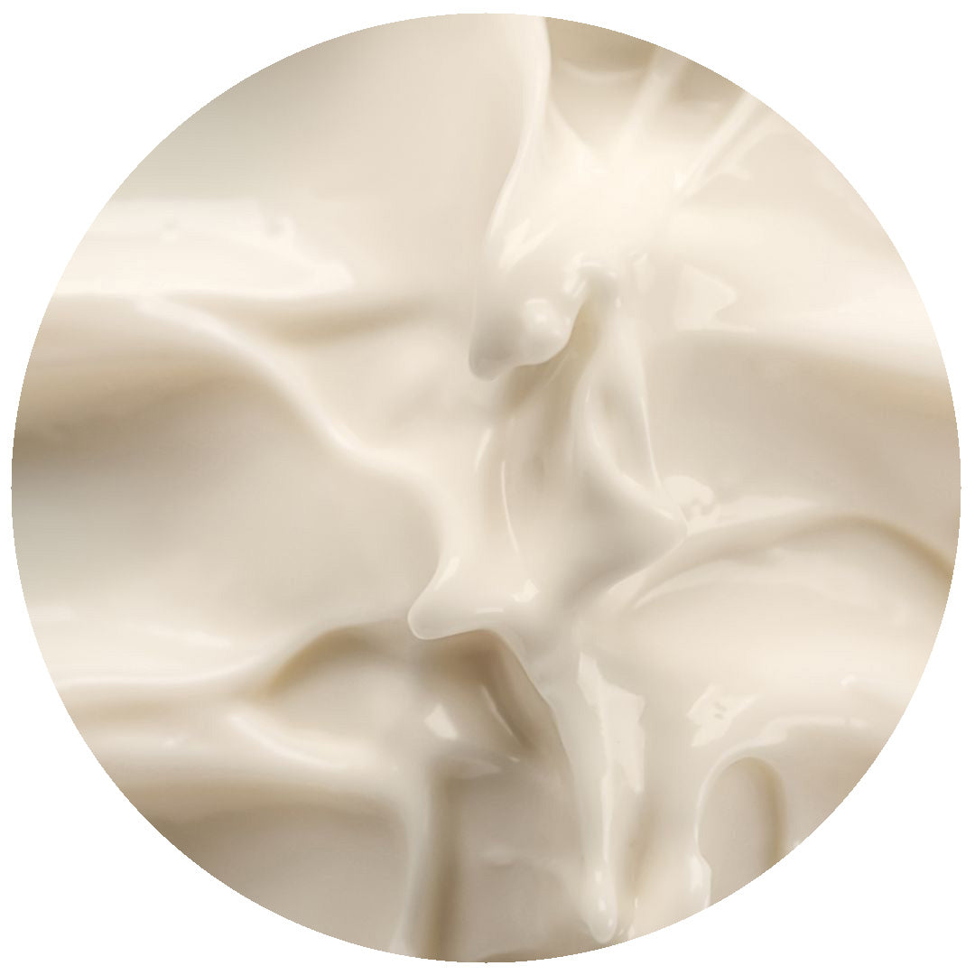 Close-up view of a creamy, smooth, white substance with a glossy texture, likely yogurt or lotion, spread unevenly within a circular frame.