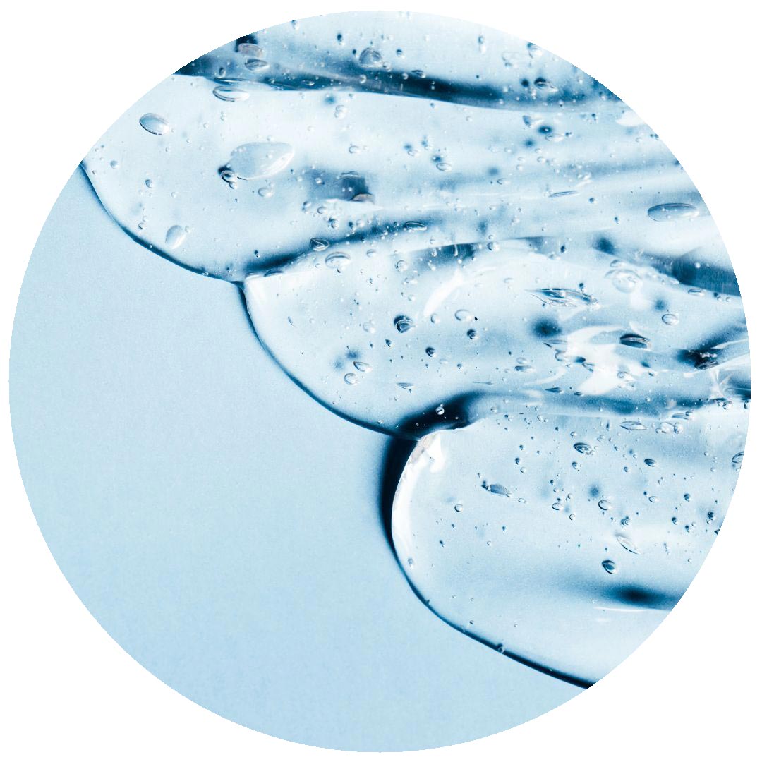 Clear gel with air bubbles spread on a light blue surface, shown inside a circular frame. The texture appears smooth and glossy, suggesting a skincare or cosmetic product.