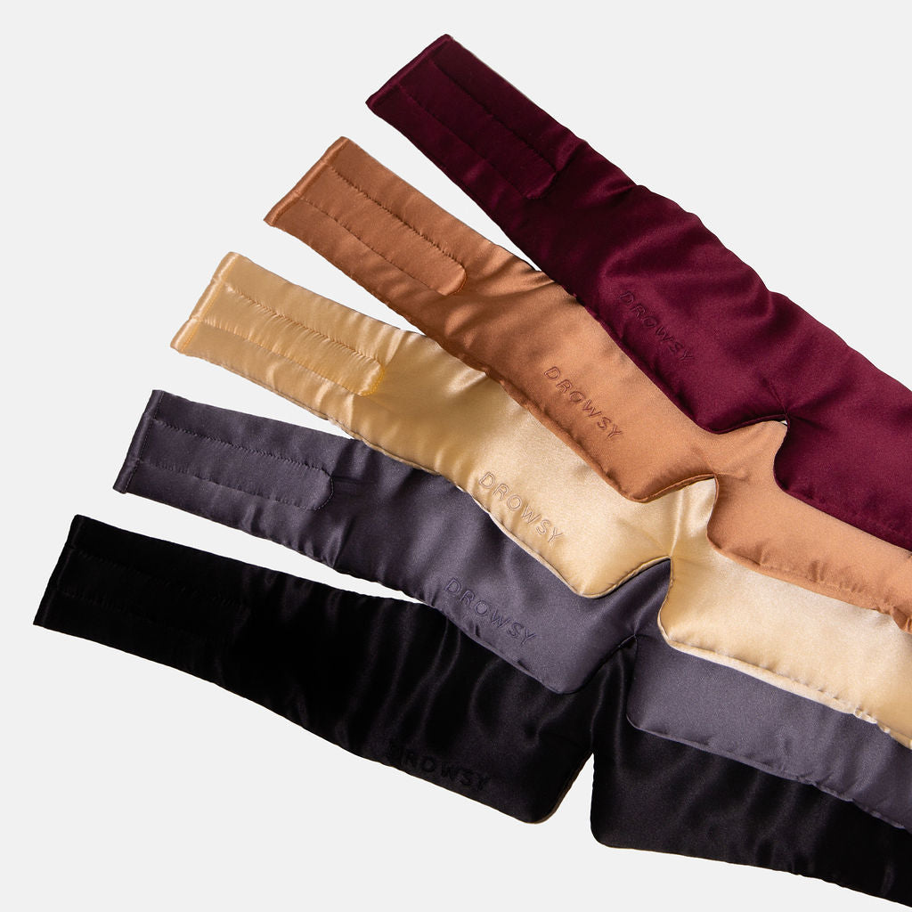 The Family Pack by drowsysleepco includes five luxury silk blackout eye masks in black, gray, gold, tan, and burgundy. Arranged in a fan shape, these padded masks feature stitched details and branding—ideal for enhancing your beauty sleep.