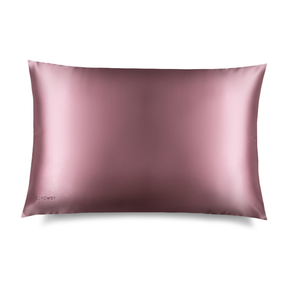 The Damask Rose Silk Pillowcase by drowsysleepco is a rectangular, mauve-colored pillowcase with a subtle sheen. "DROWSY" is printed in small letters in one corner, making it an ideal hair and skin care essential.