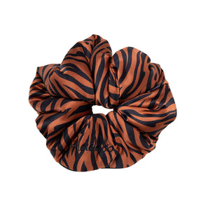 The Rajah Padded Scrunchie by drowsysleepco is an oversized silk hair accessory in black and orange tiger stripes, with "Malibu" embroidered in black—ideal for stylish hair protection.