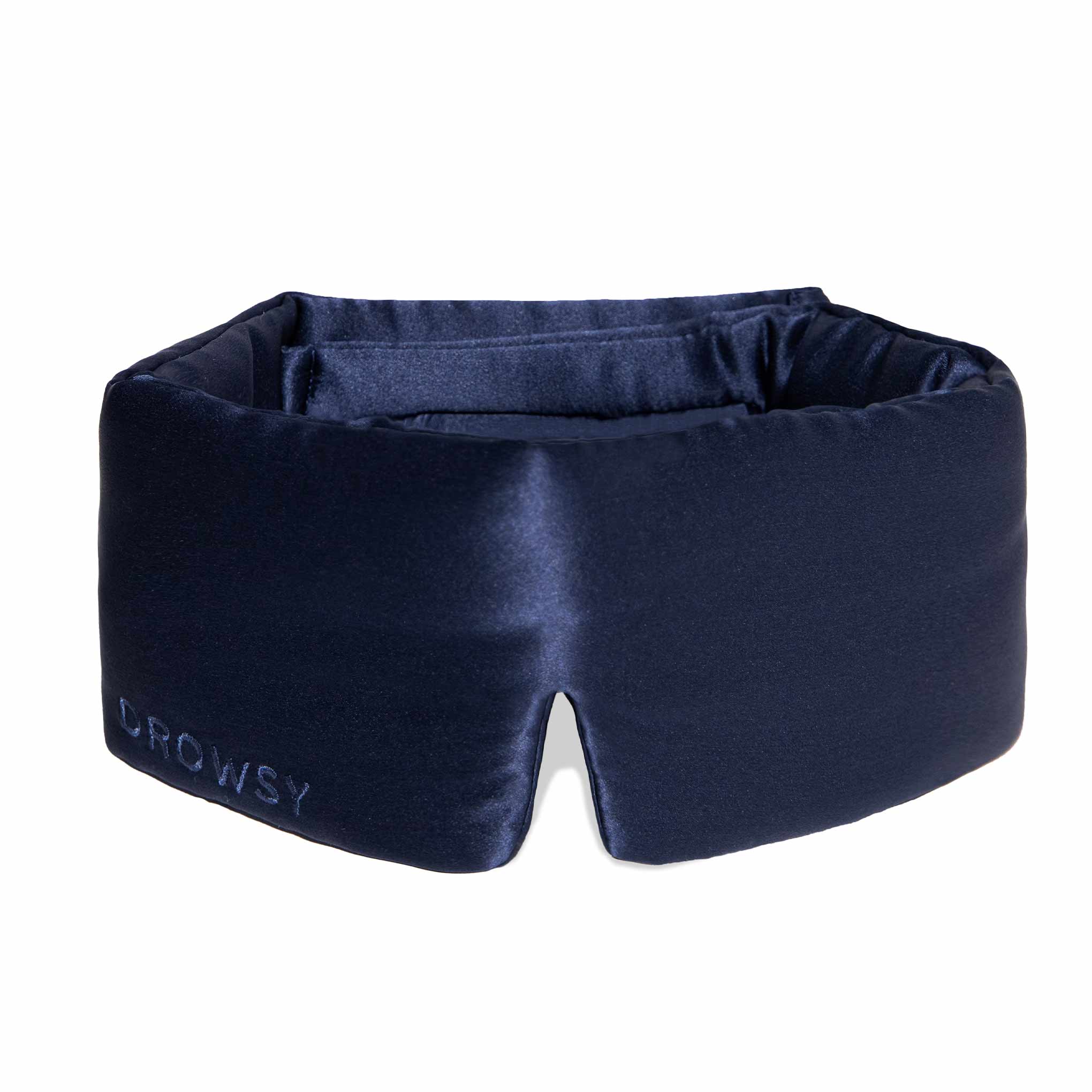 The Midnight Blue sleep mask by drowsysleepco features thick, padded sides and DROWSY embroidery on the front. Made from dark blue mulberry silk, it is designed to block out light completely for restful sleep.