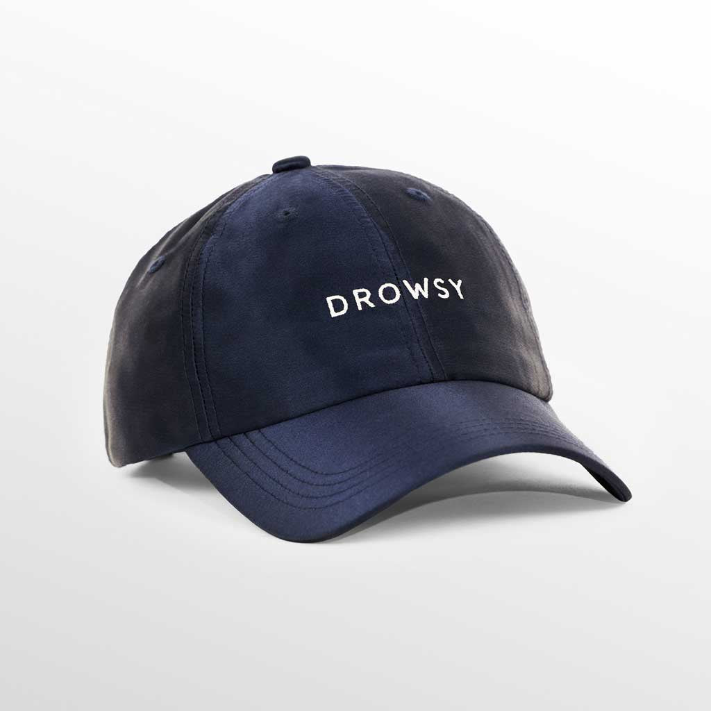 The Drowsy Silk Cap - Midnight Blue by Drowsy features white embroidered lettering on the front—perfect for outdoor workouts or keeping your hair flawless. Shown here against a simple, light background.
