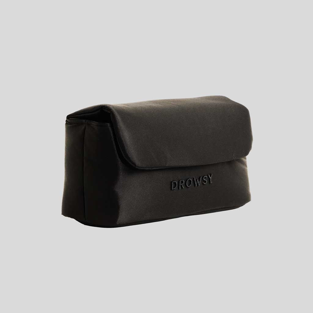 The Drowsy Silk Necessaire - Black Jade by Drowsy is a sleek black rectangular silk pouch with a flap closure and DROWSY embossed on the front, shown against a plain light gray background—ideal for elevating any beauty routine.