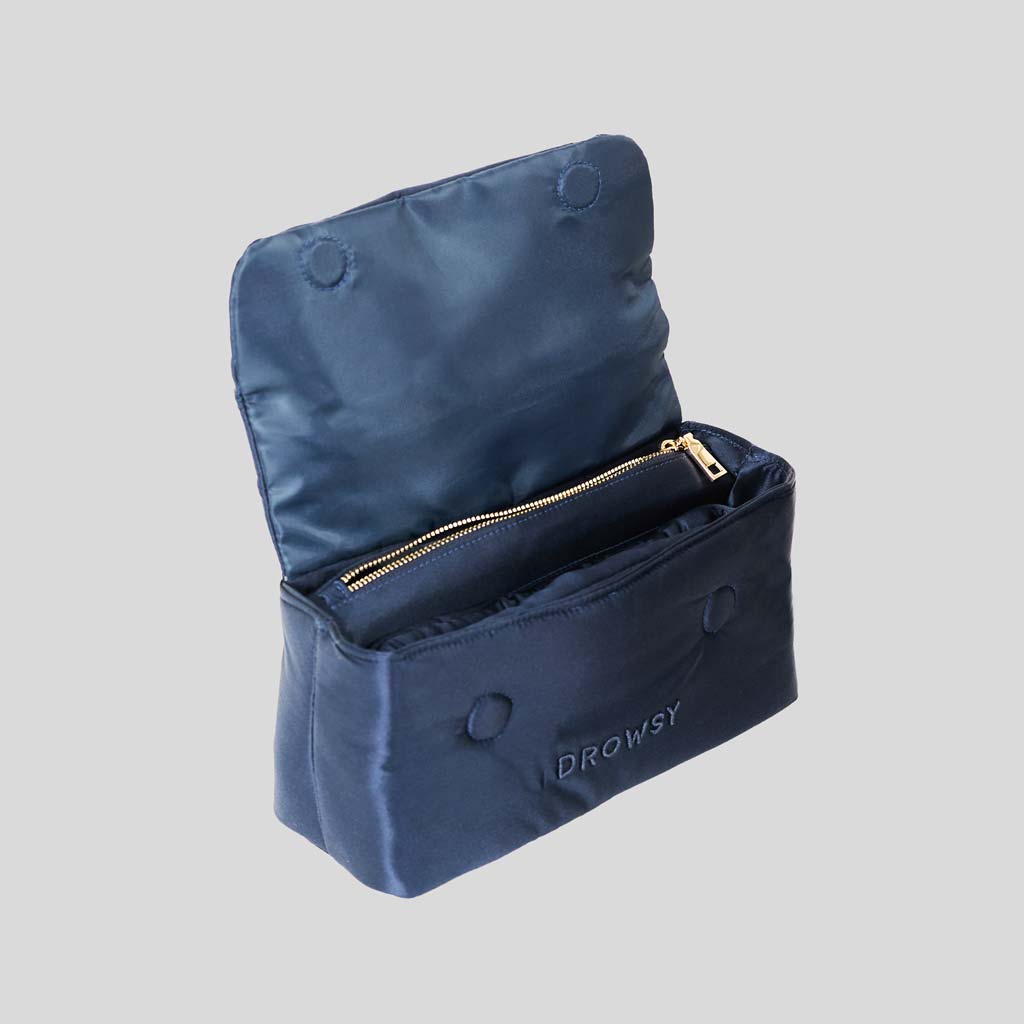 The Perfect Escape Bundle - Midnight Blue by drowsysleepco features a navy blue satin toiletry bag with an open flap and gold zipper. "DROWSY" is embossed on the front—ideal for your Silk Sleep Mask or essentials. Set against a light gray background.
