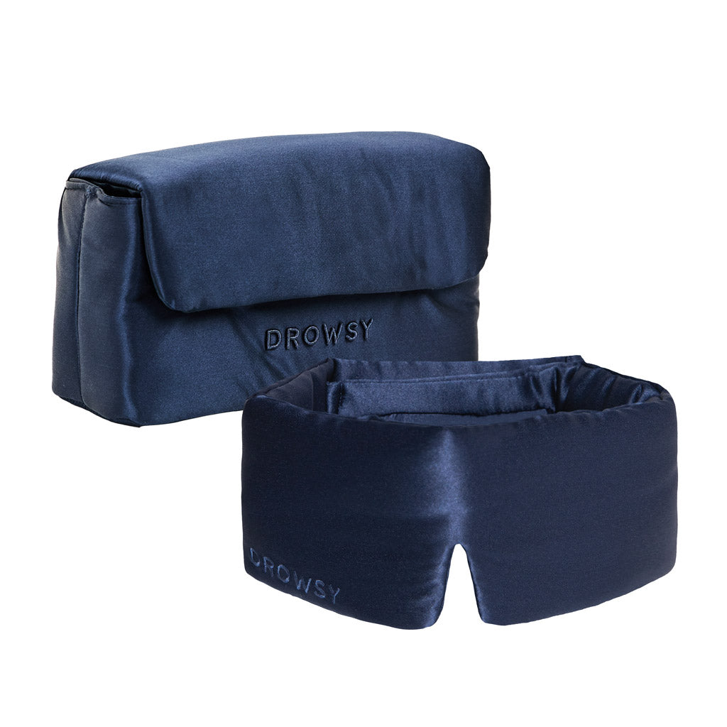 The Drowsy Sleepover Bundle in Midnight Blue features a thick, padded dark blue satin sleep mask and a matching flap-closure pouch, both embroidered with “DROWSY,” shown against a white background.