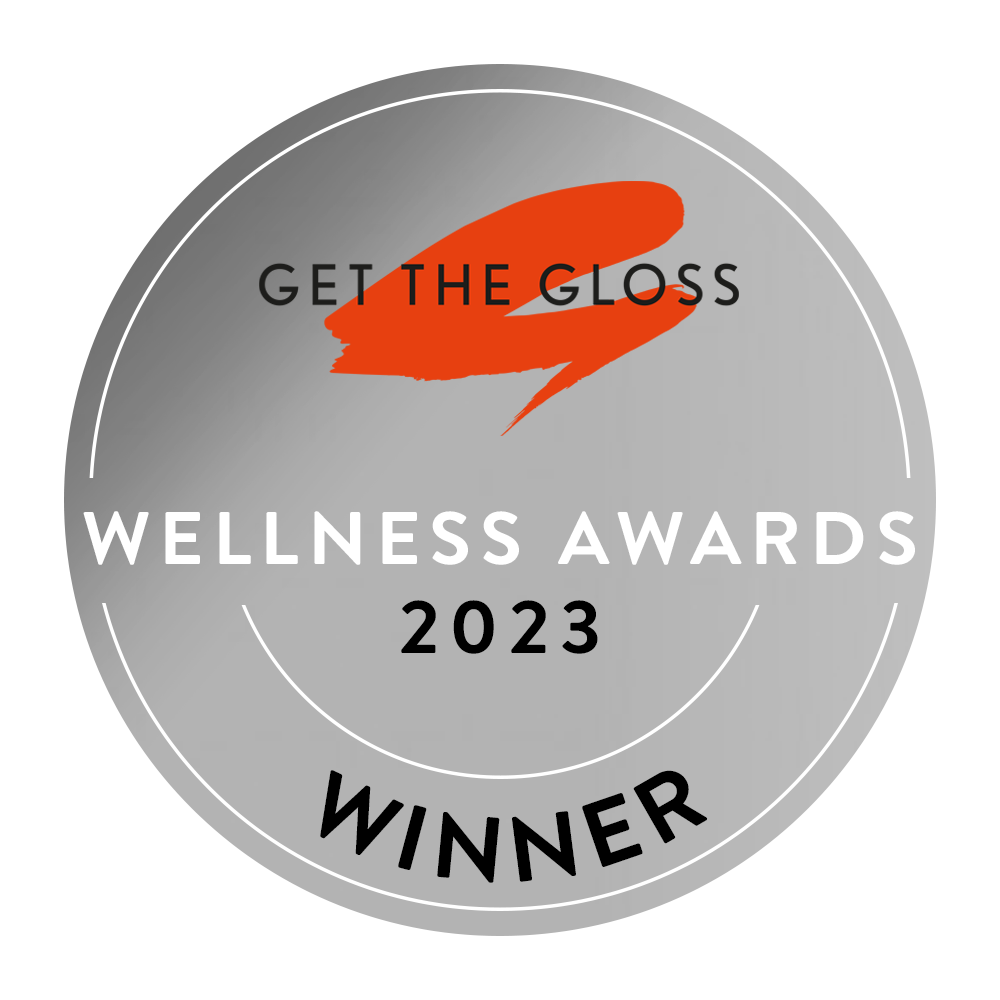 A round silver badge with Get The Gloss and an orange brushstroke at the top, Wellness Awards 2023 in the center, and Winner at the bottom.