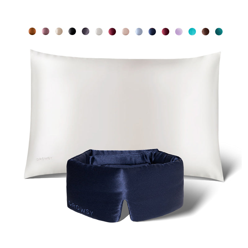 A white silk pillowcase with a navy blue sleep mask from drowsysleepco’s Sleep Week Ritual is shown. Above are circular swatches, displaying the elegant color options available for this luxurious set.