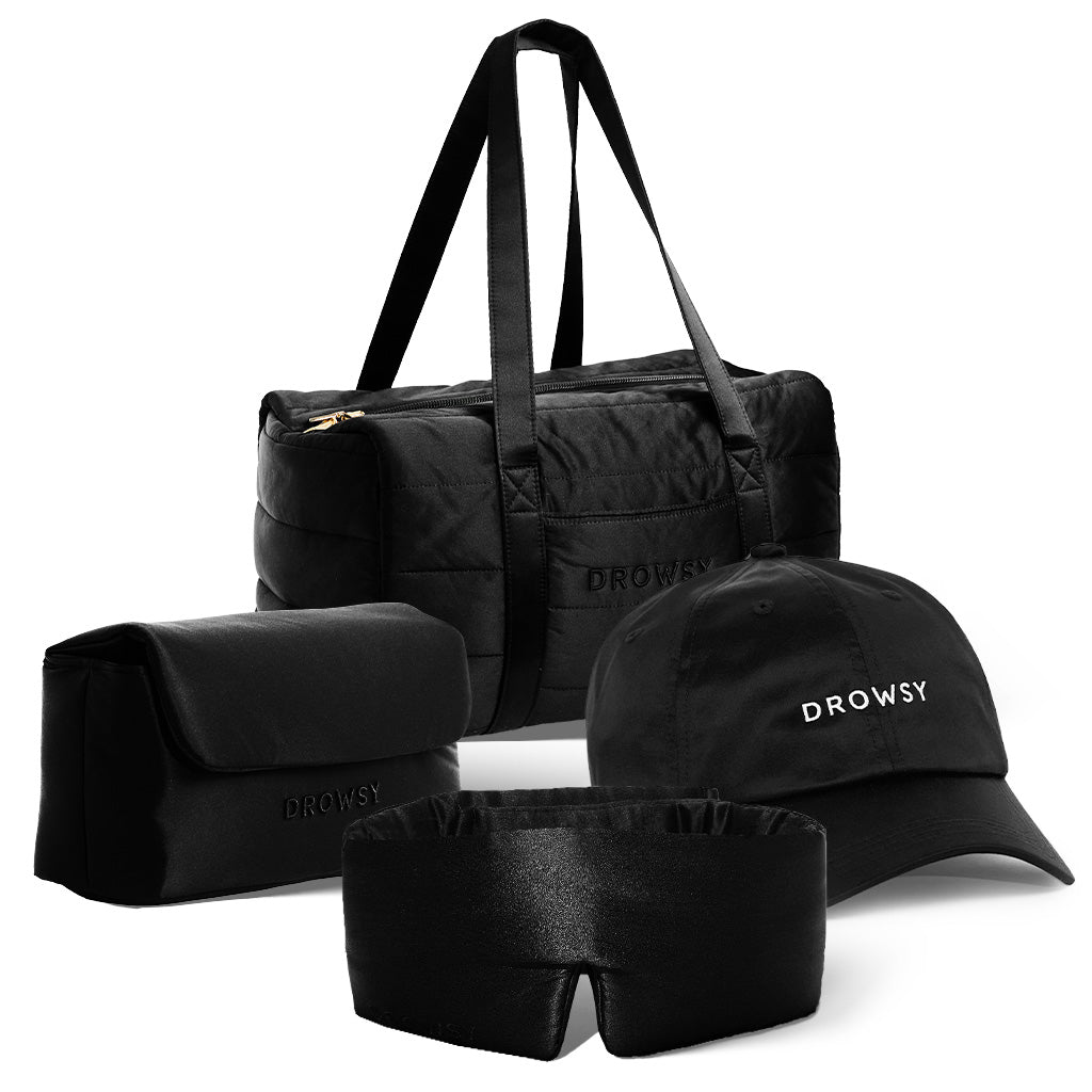 The drowsysleepco Perfect Escape Bundle – Black Jade includes a black duffel, toiletry bag, cap with white DROWSY embroidery, and a Black Jade silk sleep mask—essential beauty sleep accessories for travel, set against a white background.
