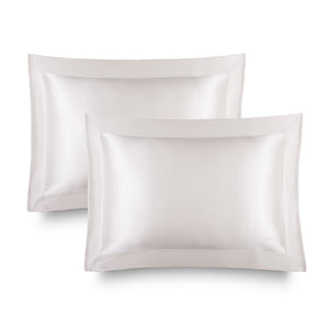 Two Hyalo Pillowcases – Akoya Pearl by us.drowsysleepco, crafted in lustrous white silk with a shiny, smooth texture, are neatly stacked and slightly overlapping against a clean white background—perfect for boosting overnight hydration and supporting your skin’s natural moisture balance, just like hyaluronic acid.