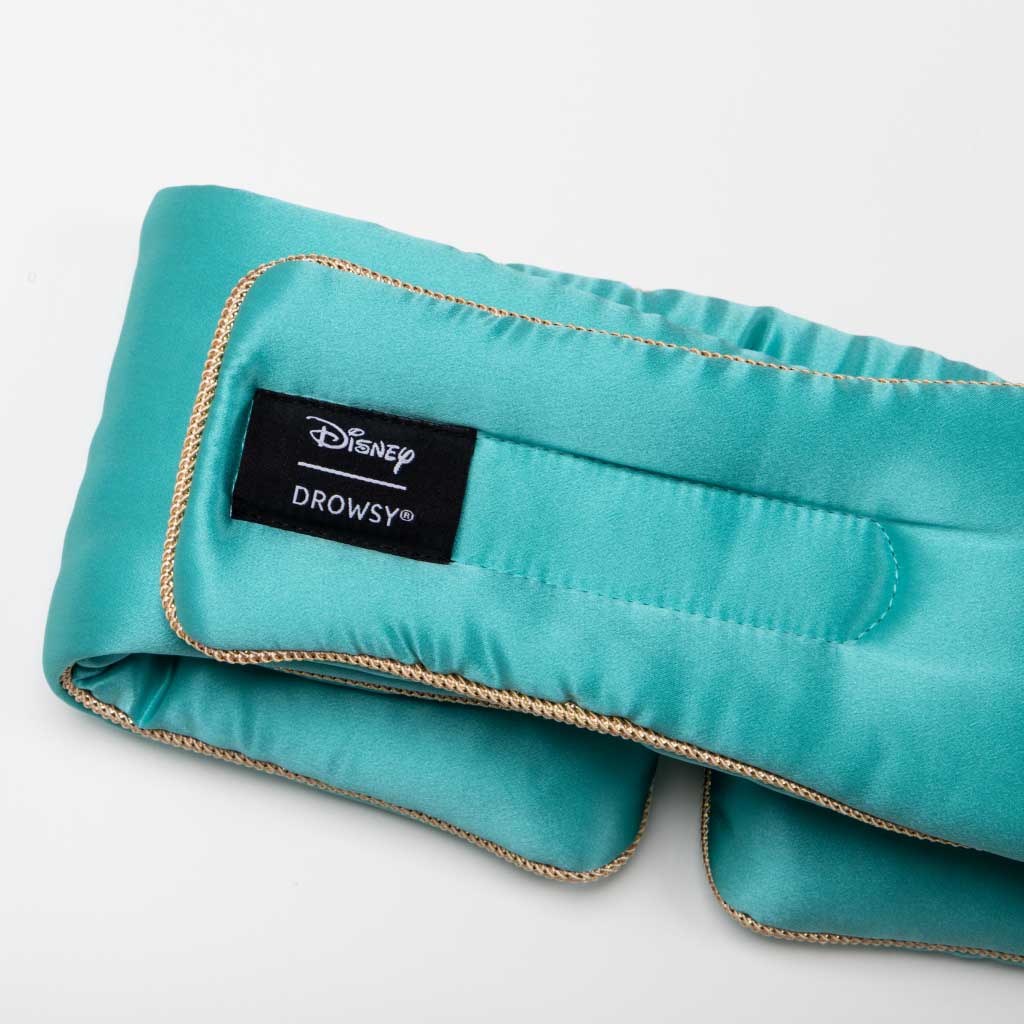 A teal satin Jasmine Jewel Sleep Mask by drowsysleepco, with gold trim and a black "Disney Drowsy" label in white text, is shown on a white background.
