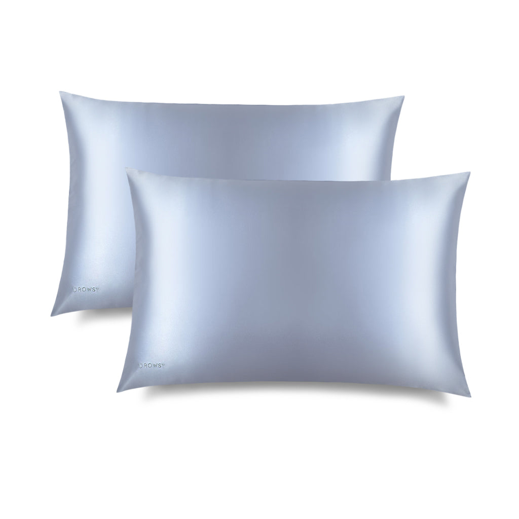 Two Blue Belle Silk Pillowcases by drowsysleepco, in light blue silk with a smooth, shiny finish, are arranged overlapping on a white background—a nightly essential for hair protection and skincare.