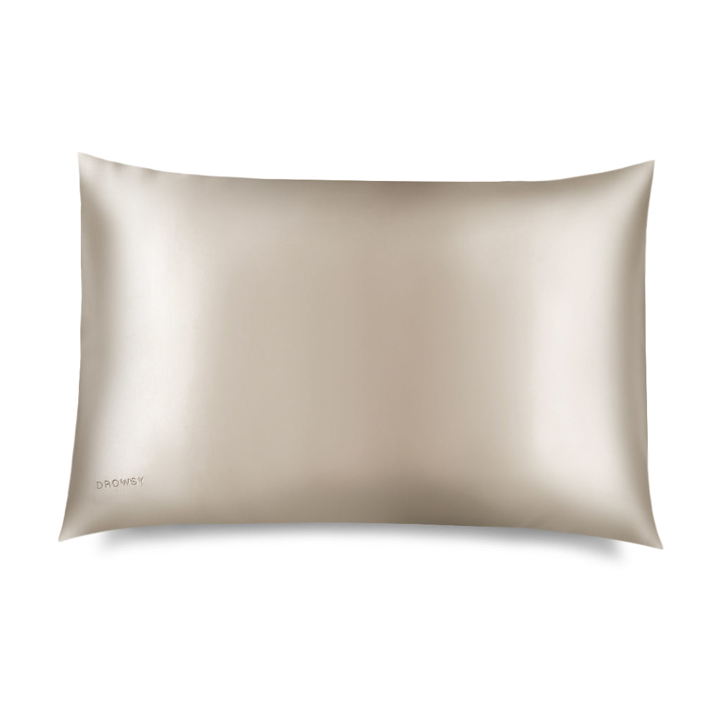 A Dusty Gold Silk Pillowcase with a subtle sheen is displayed on a white background. DROWSY appears in small letters at the bottom left—a hair-protecting, skincare-essential silk pillowcase.