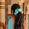 A woman with the drowsysleepco Jasmine Padded Scrunchie, a blue oversized accessory, in her hair.