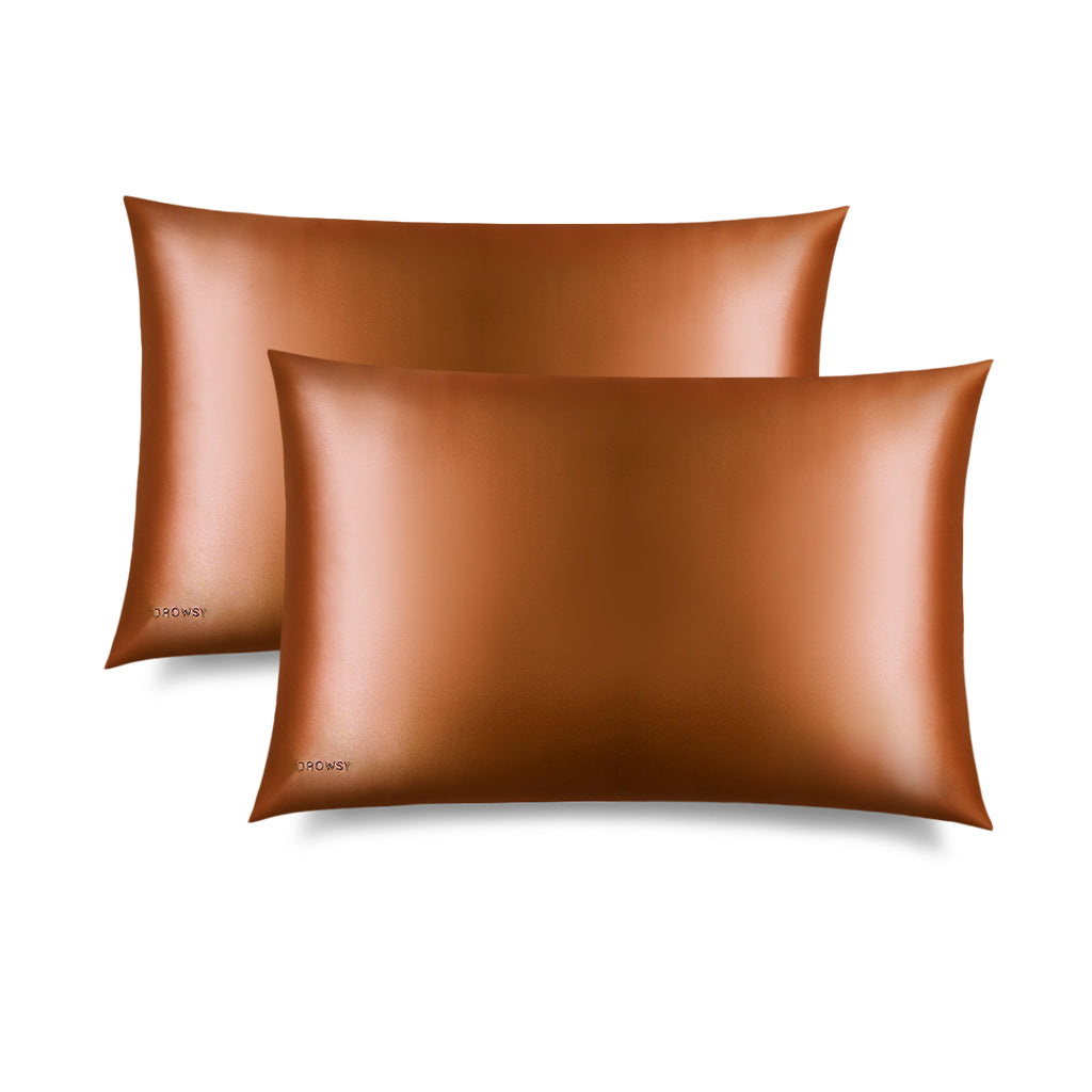 Two rectangular Pumpkin Spice Silk Pillowcases by drowsysleepco, in brown silk with a subtle logo, are shown overlapping on a white background. These pillowcases protect hair and help reduce sleep creases for smoother mornings.