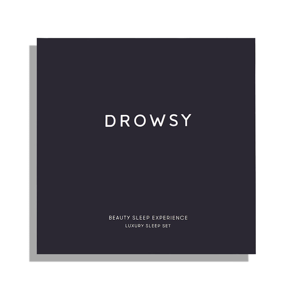A black square box from drowsysleepco with “DROWSY” in large white text, and below in smaller letters, “BEAUTY SLEEP EXPERIENCE” and “LUXURY SLEEP SET.” The packaging hints at a luxury sleep accessory inside and features a slight left shadow.