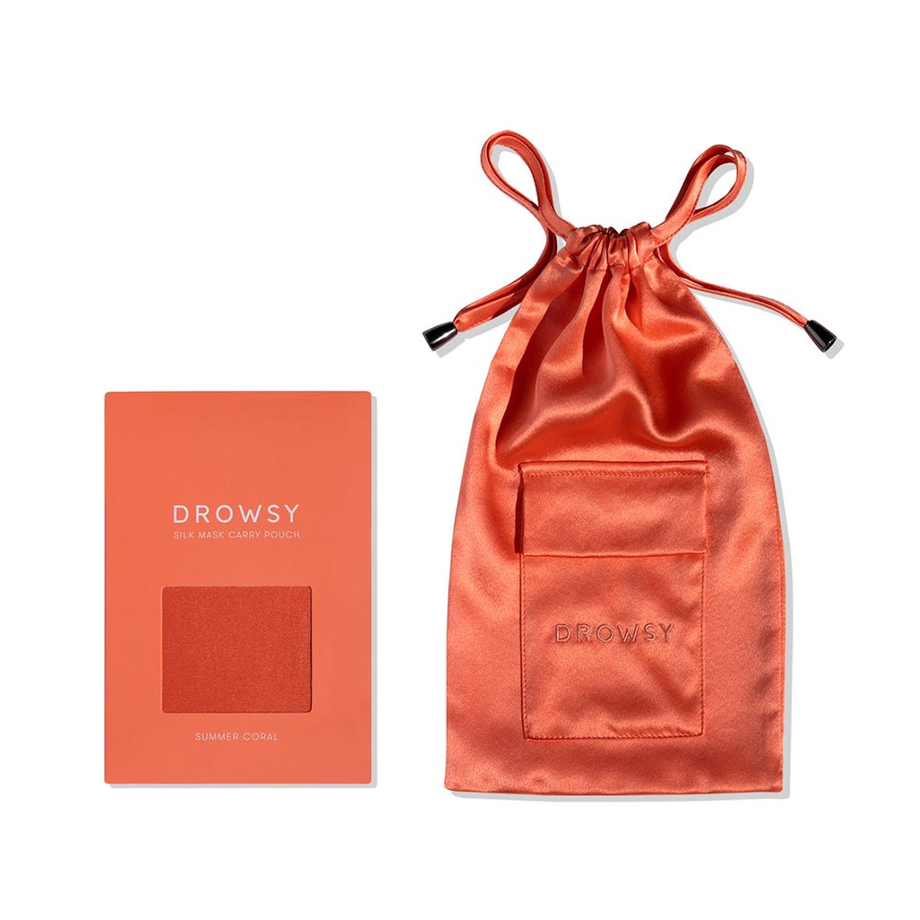 The drowsysleepco Summer Coral Silk Carry Pouch, made from orange mulberry silk with a drawstring and front pocket, sits beside its matching packaging. The box includes a fabric sample in the same vibrant shade as the pouch.