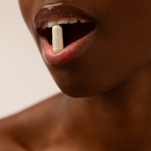 A close-up of a person’s mouth gently holding a white Supplements - Beauty Sleep Clinic pill by drowsysleepco between their lips, with slightly parted lips and visible skin, suggesting use of a sleep supplement.