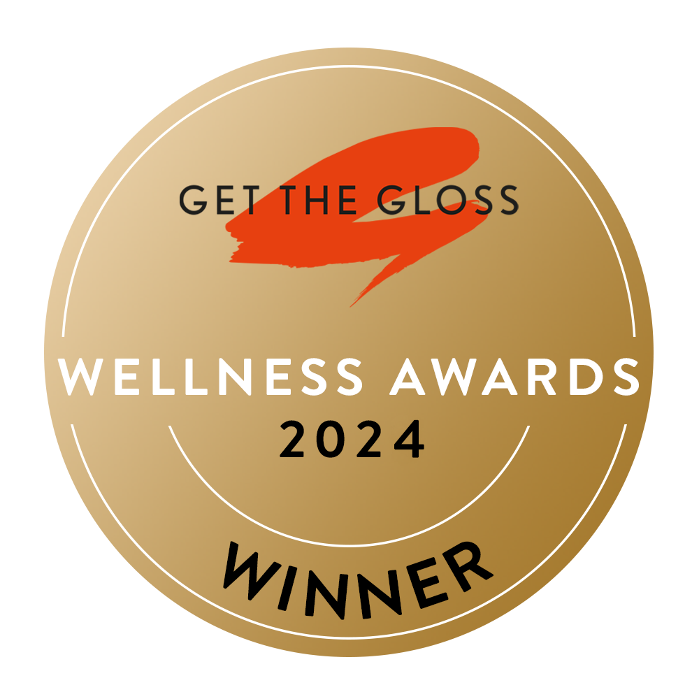 A gold circular badge with Get The Gloss Wellness Awards 2024 Winner written on it, featuring a red swoosh graphic at the top.