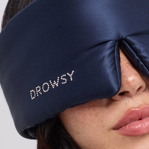 A person wears the drowsysleepco Midnight Blue sleep mask, featuring a Swarovski®-embellished logo across the eyes. Only the lower half of their face—including closed lips and part of the nose—is visible, capturing a serene moment of beauty sleep.